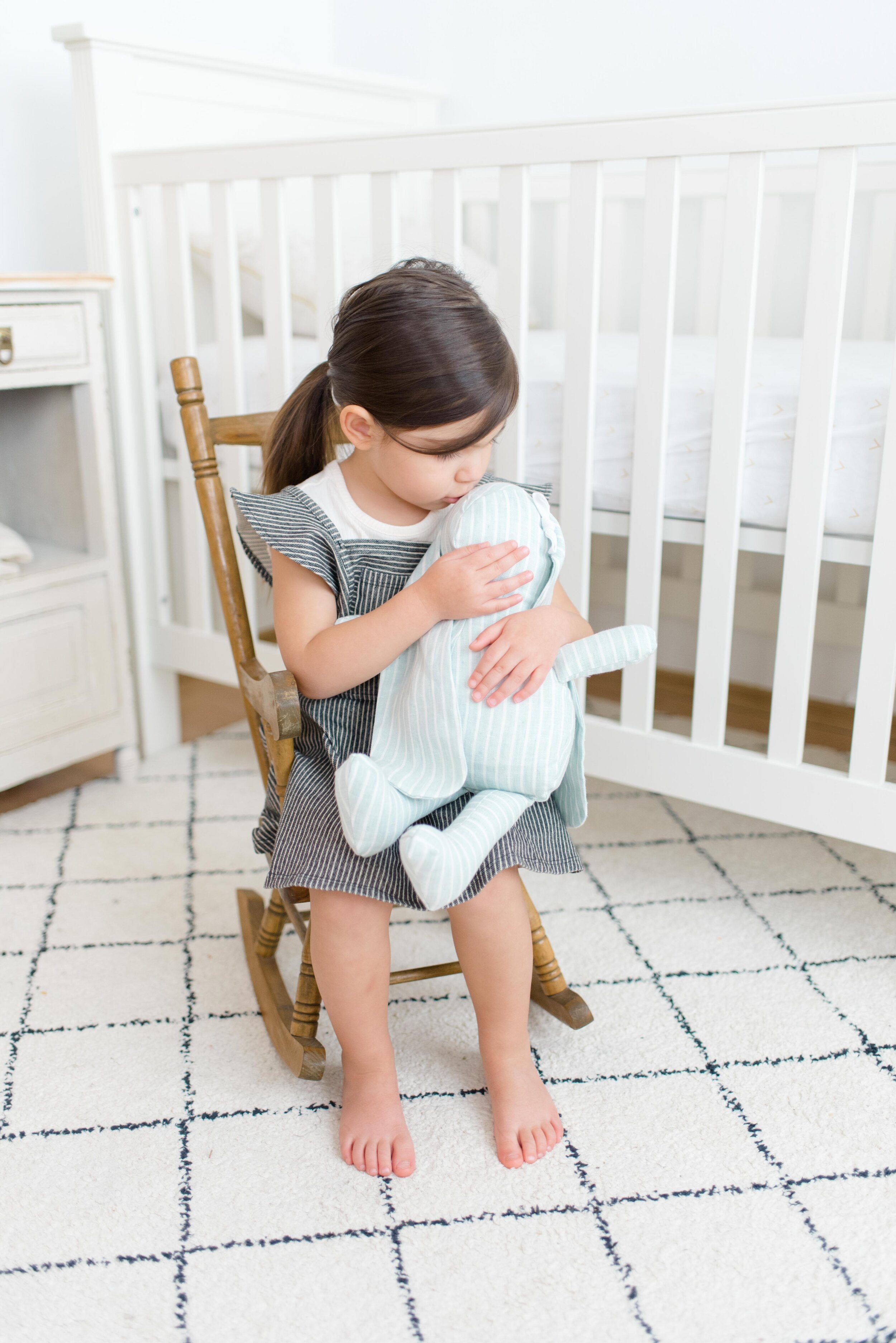 Young girl in rocking chair holding light green linen stuffed bunny